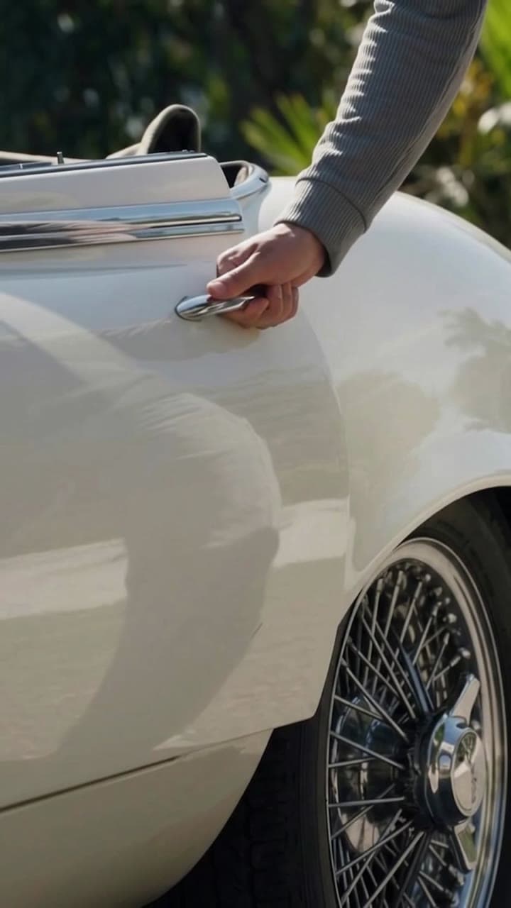 Hand opening the door of a white classic car